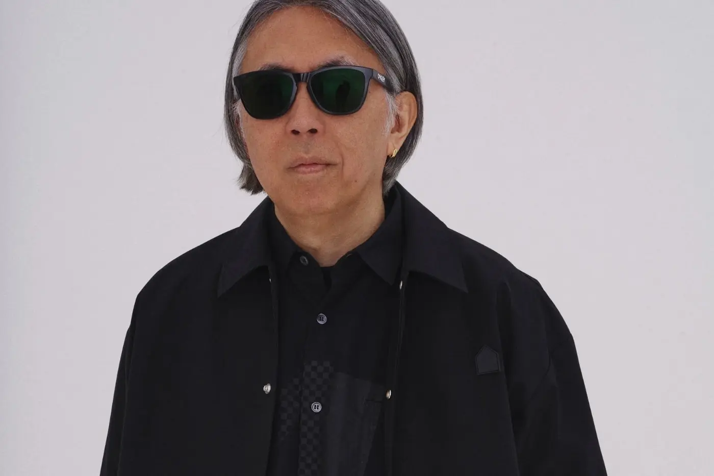Hiroshi Fujiwara wearing DSM Kei Ninomiya FW26 football-inspired garment with hand-stitched floral overlay