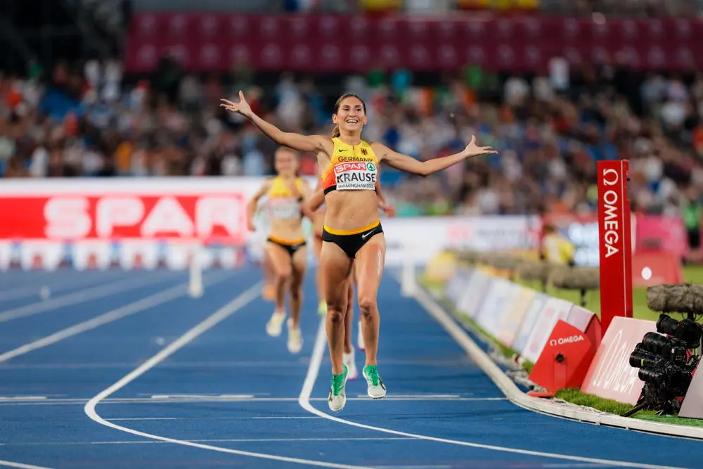 On athlete celebrating a medal in competition kit and racing spikes