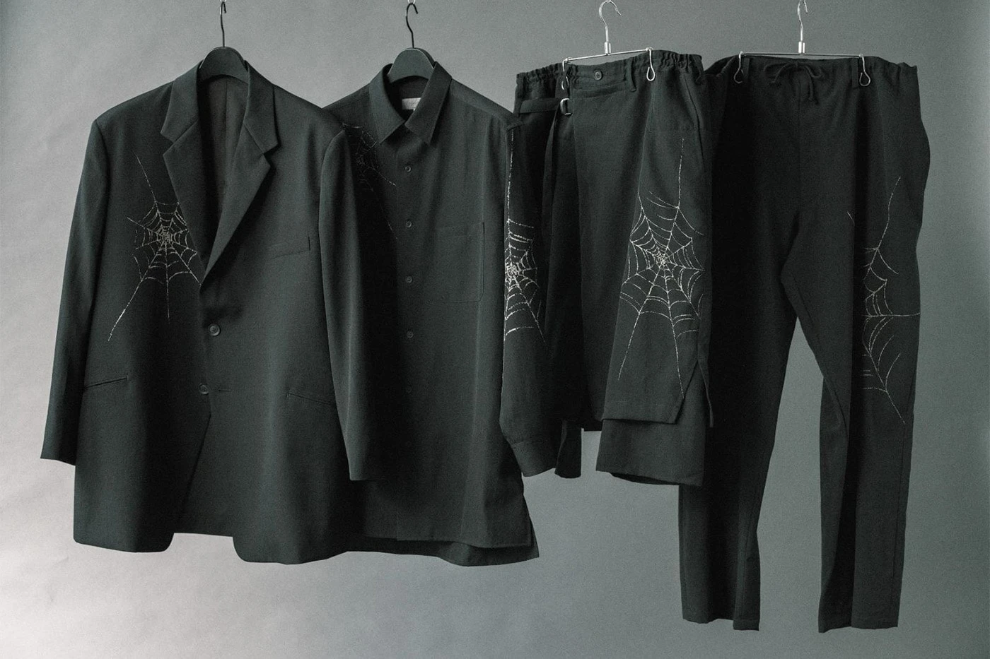 Black wool gabardine jacket with a discharge-printed spider web lattice visible across the torso